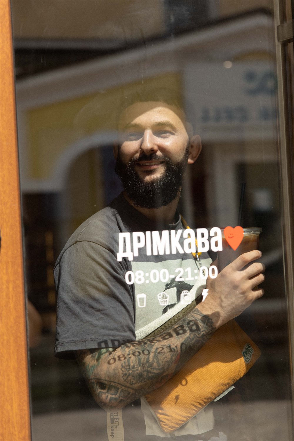 Бариста у футболці ДРІМКАВА за вітриною кавʼярні